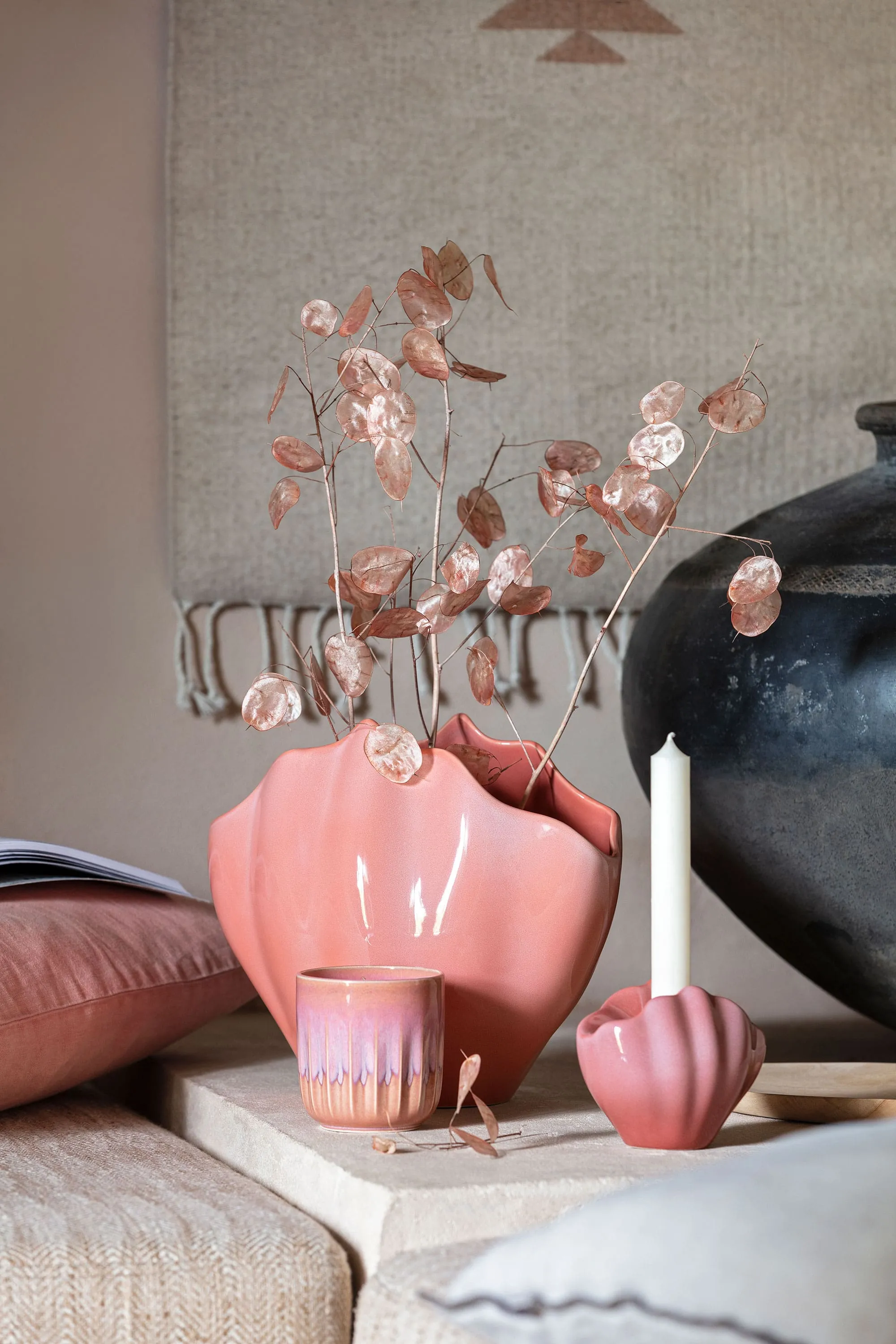 Un vase Perlemor à côté d’une bougie Un vase décoratif Perlemor rose se tient sur une table à côté d’une bougie.