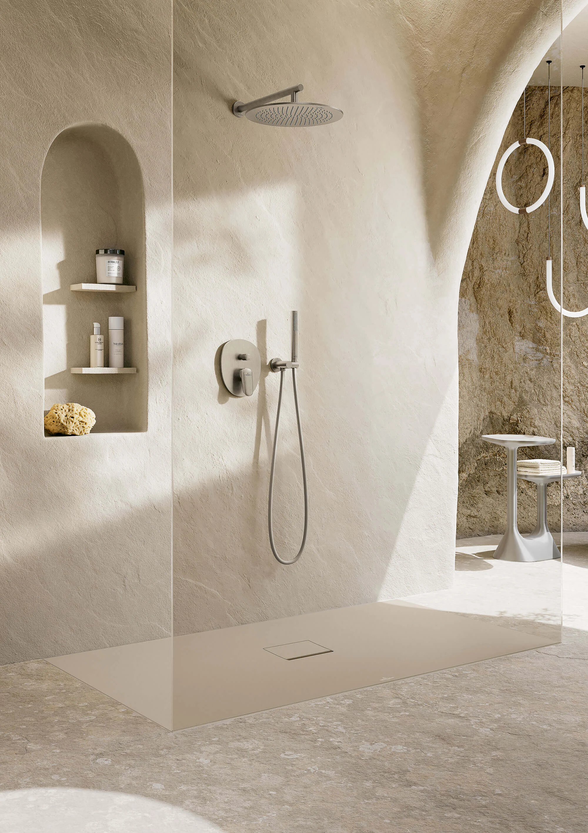 Douche à l'italienne moderne en forme d'arc avec carrelage en mosaïque, étagère intégrée et robinetterie minimaliste dans des tons neutres.