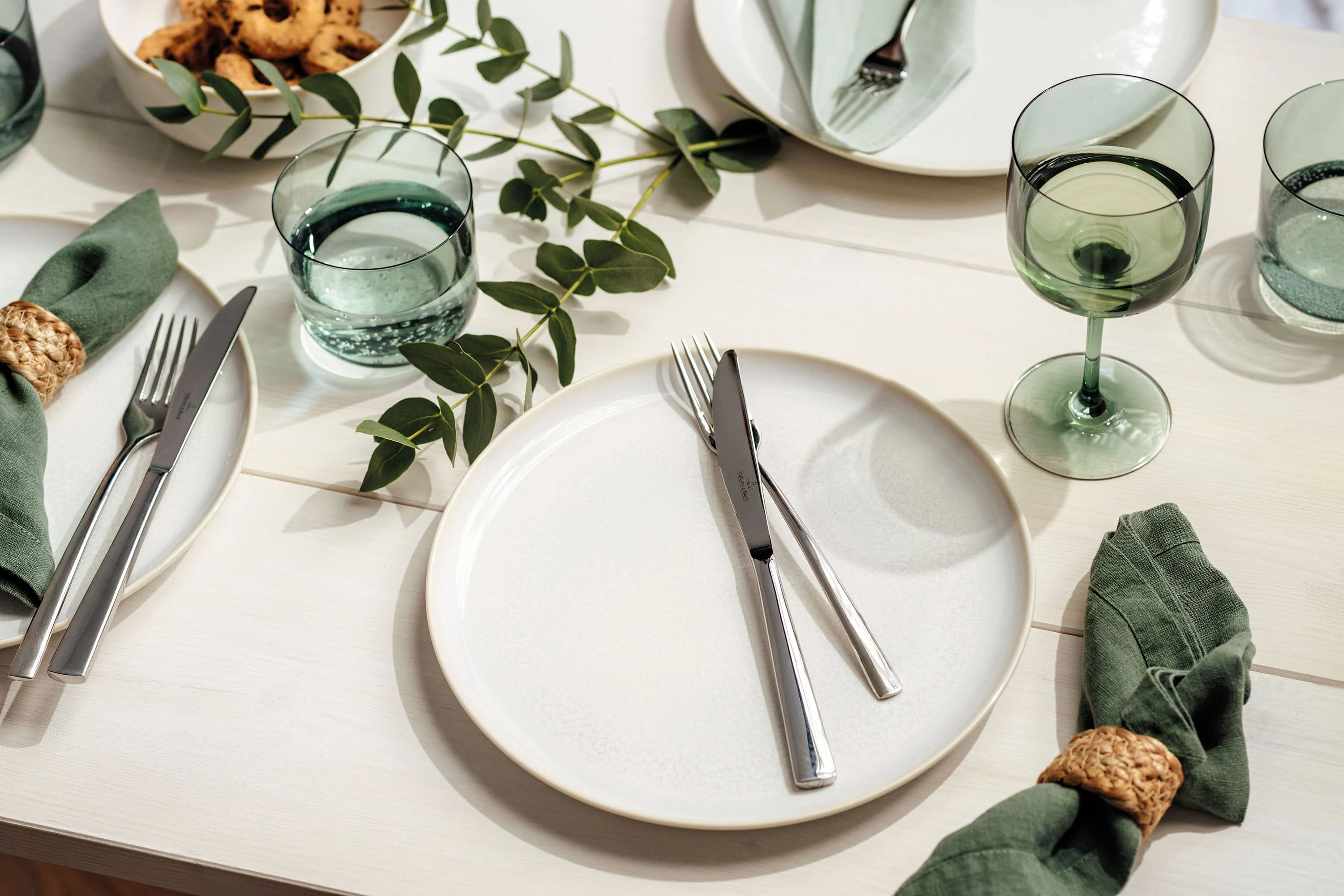 Ein heller Holztisch ist mit Crafted Cotton Geschirr eingedeckt. Die grünen Like Gläser setzen schöne Akzente im Vintage Look.