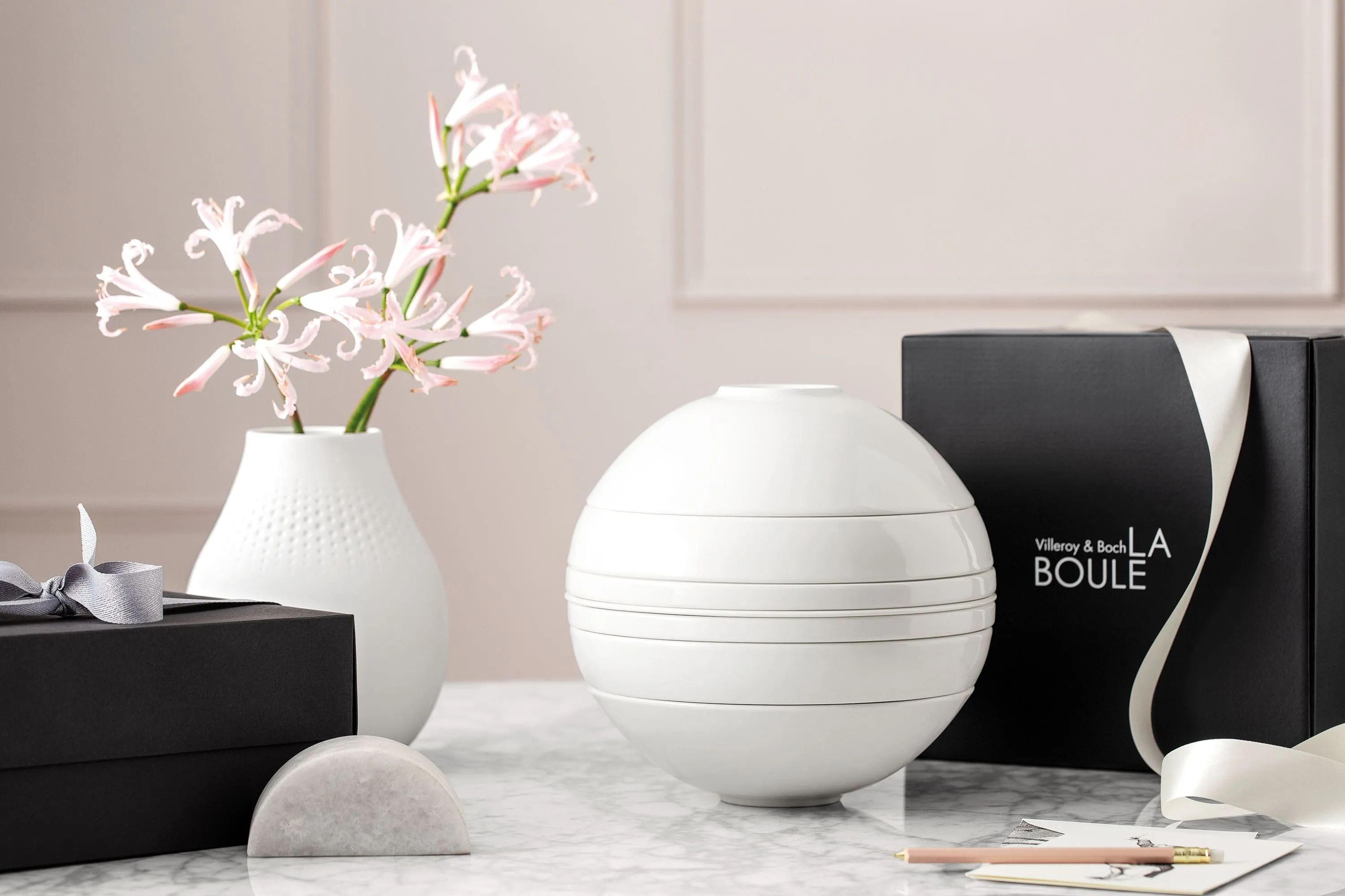 A white La Boule tableware set on a table with a black gift box behind it.