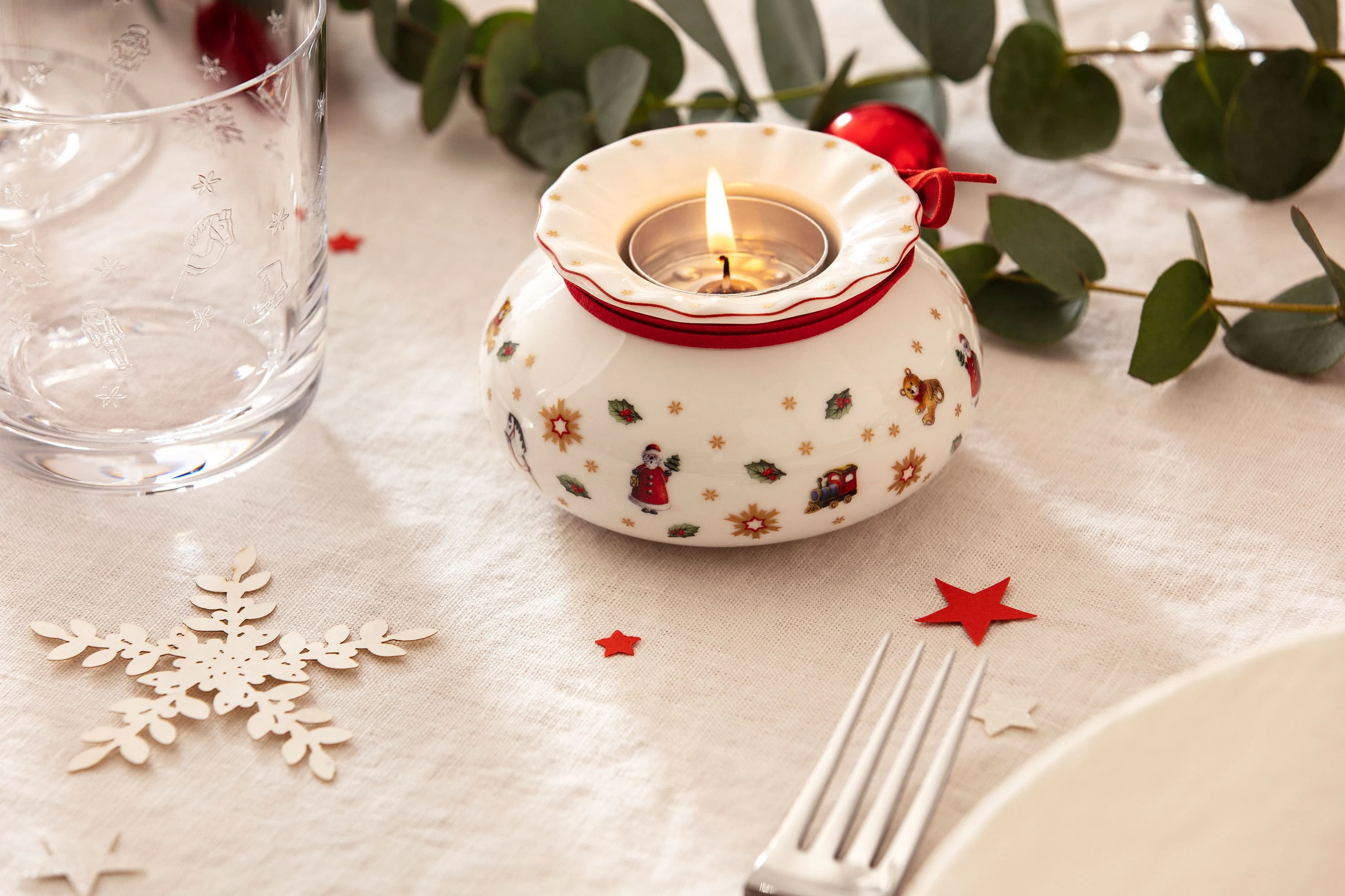 Festive table decoration with a Toy's Delight tea light holder Festive table decoration with a Toy's Delight tea light holder surrounded by green and red accents.