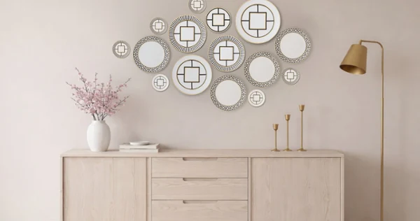 metrochic plates on a wall as art A minimalist living room features a wooden sideboard, decorative circular mirrors on a beige wall, a vase with pink flowers, and a gold floor lamp. Calm, elegant atmosphere.