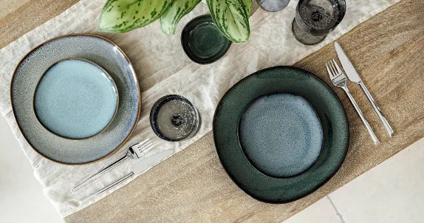 Lave Collection Plates – Top View of a Modern Table Arrangement Top-down view of a modern table arrangement featuring dinner and bread plates from Villeroy & Boch’s Lave collections: Lave Vert, Lave Beige, and Lave Glacé. The clean composition highlights the unique reactive glazes and natural textures of each plate on a neutral tabletop, with no food present, emphasizing the artisanal elegance of the stoneware