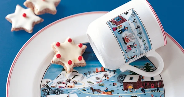 Design Naif Christmas mug placed on a plate with a star shaped cookie.