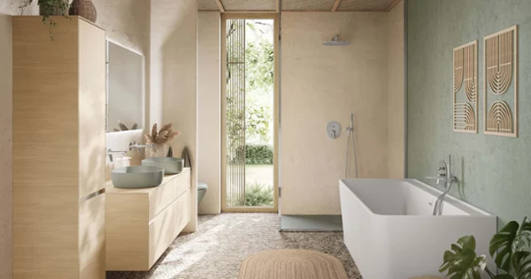 Miska WC w łazience w stylu boho Wisząca miska WC Antao marki Villeroy & Boch w kolorze zielonym na tle strukturalnej beżowej ściany i kamiennej podłogi. Z boku wiszą ręczniki.