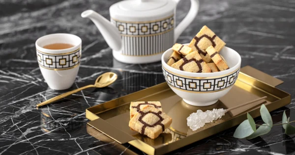 Elegant MetroChic tea set with a teapot and a cup Elegant MetroChic tea set with a teapot and a cup on a gold tray, on a marble table.