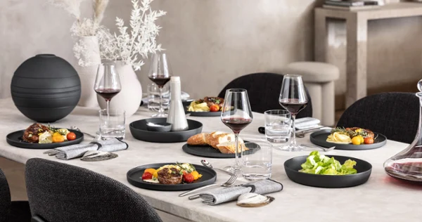 A dining table with a black La Boule being used with food as well as an assembled La Boule as decoration.