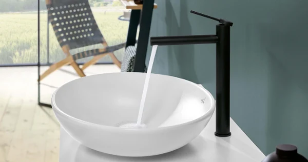 Biała umywalka Loop & Friends z baterią Biała umywalka stojąca na blacie Loop & Friends w łazience z krajobrazem w tle