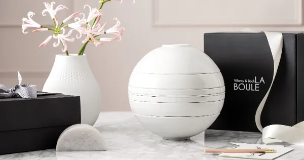 La Boule White with gift box A white La Boule dinnerware set on a table with a black gift box behind it.