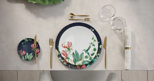 Place setting with Avarua plate and golden MetroChic flatware A table setting with floral pattern dinnerware from Avarua and golden MetroChic flatware.