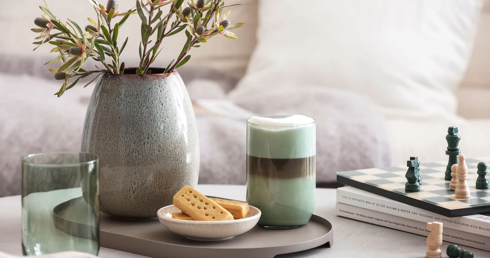  Like Sage glass with coffee, a chessboard, biscuits and a Lave vase with pampas grass on a tabletop.