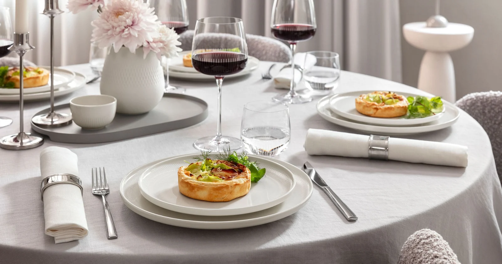 Elegant table set for four featuring Afina porcelain dinnerware and Maxima red wine glasses filled with wine. Served with food in a refined, modern dining atmosphere.