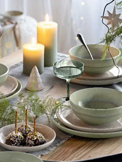 Festive table with green and beige Perlemor plates, surrounded by Winter Glow candleholders and Like glasses.