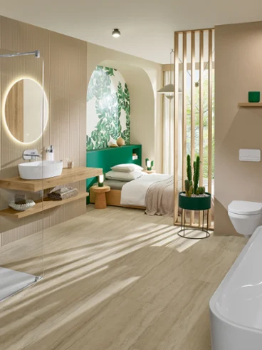 Open-plan bathroom with a white a walk-in shower, a freestanding bath and travertine-look surfaces, connected to a bedroom.
