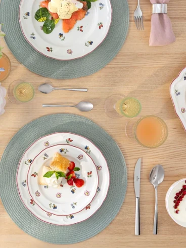 Petite fleur table mobile hotspot A set dining table for four people with Petite Fleur flower plates, pink napkins, drinks, and a floral arrangement.