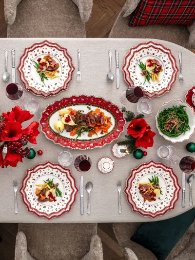 Ein festlich gedeckter Esstisch Ein festlicher Esstisch für acht Personen mit rot-weiß gemusterten Tellern, roten Blumen, Gläsern, Besteck und verschiedenen Gerichten, darunter Pasta und Salat, auf einer weißen Tischdecke.