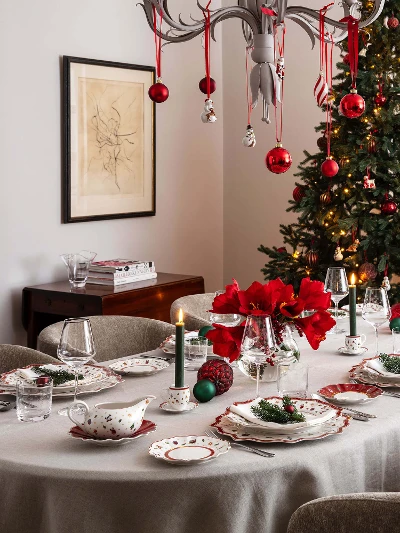 Toy's Delight crockery in a festively decorated dining room Festively decorated dining room with a table set for eight people. The table is set with festive crockery, candles and red flowers. Next to it is a Christmas tree with ornaments.