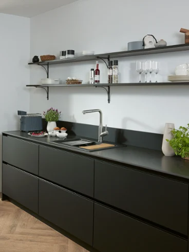 Subway Style Shower kitchen tap in a black kitchen A Subway Style Shower solid stainless-steel kitchen tap in a black kitchen with shelves and sink.