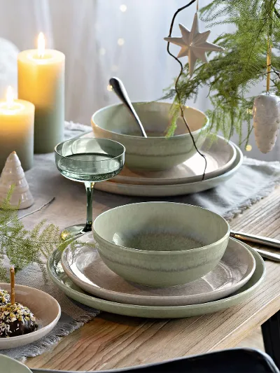 Festive table with green and beige Perlemor plates, surrounded by Winter Glow candleholders and Like glasses.