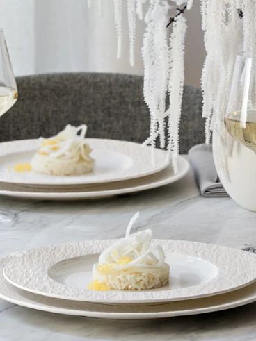 Dressage de table élégant avec deux assiettes Manufacture Dressage de table élégant avec deux assiettes Manufacture de dessert, des verres à vin et un décor blanc sur une surface en marbre.