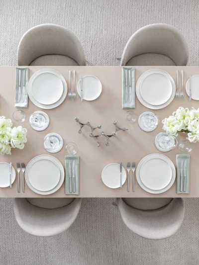 Afina dinnerware with Piemont flatware on a beige dining table Elegant dining table, set for six people, with white Afina dinnerware, Piemont flatware and floral centerpieces.