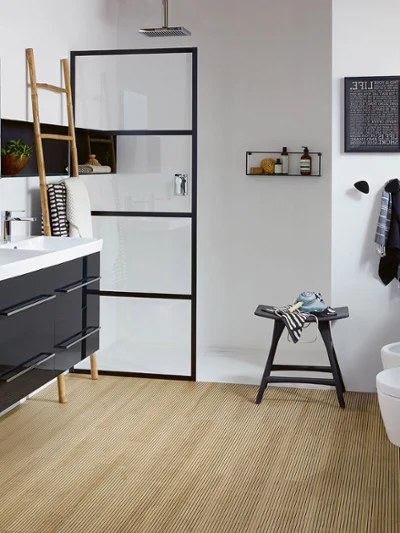 Bathroom from the Villeroy & Boch Avento collection Modern bathroom with a double washbasin, a black-framed shower, a wooden floor, a wall-mounted toilet and bidet, a clock, a ladder shelf and various decorative objects.