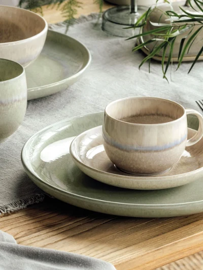 Perlemor green and beige plates on a wooden table Rustic table decoration with Perlemor plates and cups in subtle earthy colours on a wooden table.