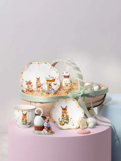 A decorative Annual Easter Edition 2026 basket A decorative Annual Easter Edition 2026 basket with bunny-themed plates, cup, figurine, cookies, eggs, and a green ribbon.