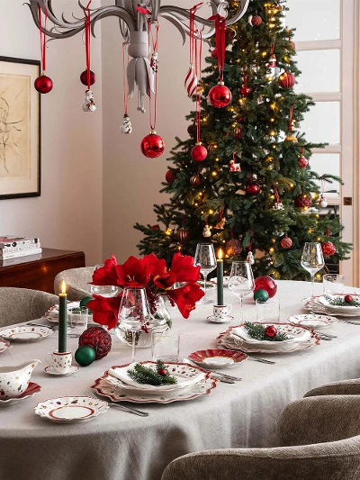 Toy's Delight crockery in a festively decorated dining room Festively decorated dining room with a table set for eight people. The table is set with festive crockery, candles and red flowers. Next to it is a Christmas tree with ornaments.