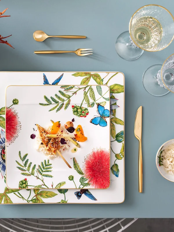 Ein gedeckter Tisch mit Amazonia-Tellern, mit goldenem MetroChic Besteck von Villeroy & Boch.