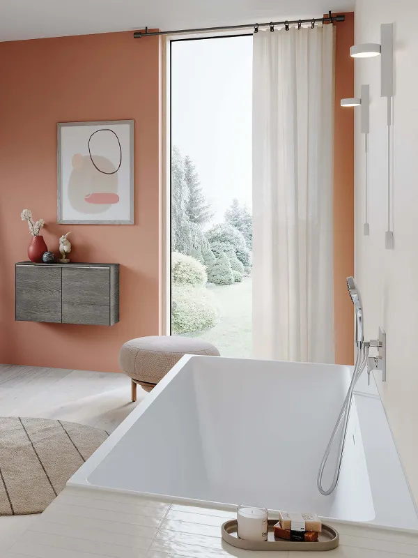 A modern bathroom with orange-coloured walls and a white Subway 3.0 bath.