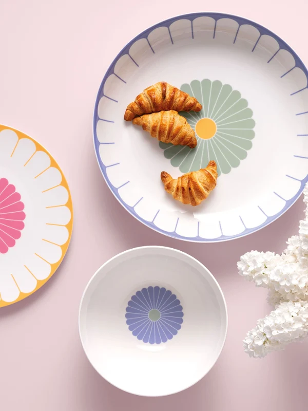 Three Villeroy & Boch Fleur plates Three Villeroy & Boch Fleur plates with croissants and macarons next to white flowers on a light pink background.