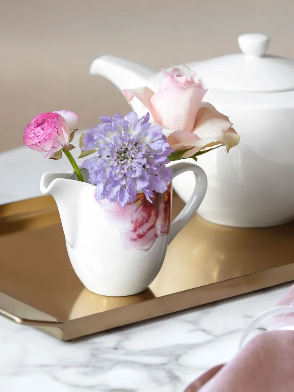 Elegant tea service with a white For Me teapot and a Rose Garden milk jug decorated with fresh flowers on a gold tray.