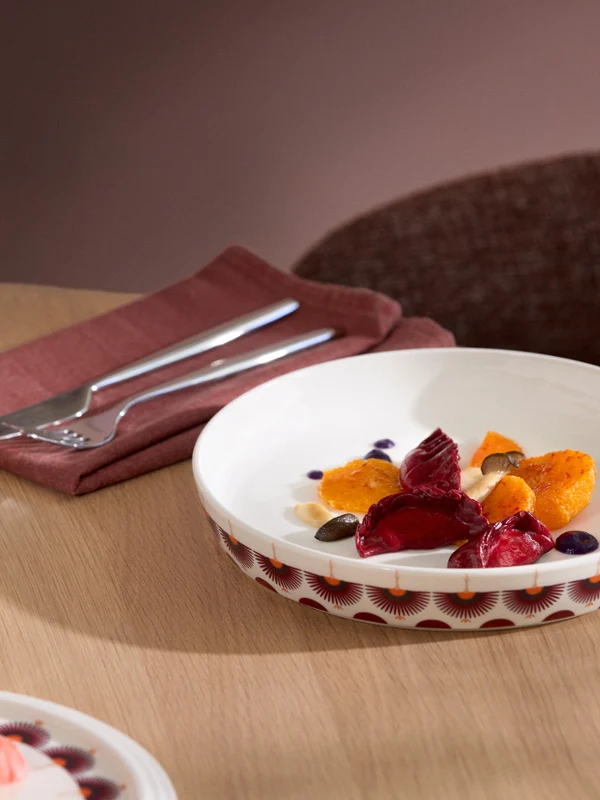 La Boule Kyoto with food On a table sits a La Boule Kyoto dessert plate with fruit and sauce—next to a wine glass, cutlery, and a folded napkin.
