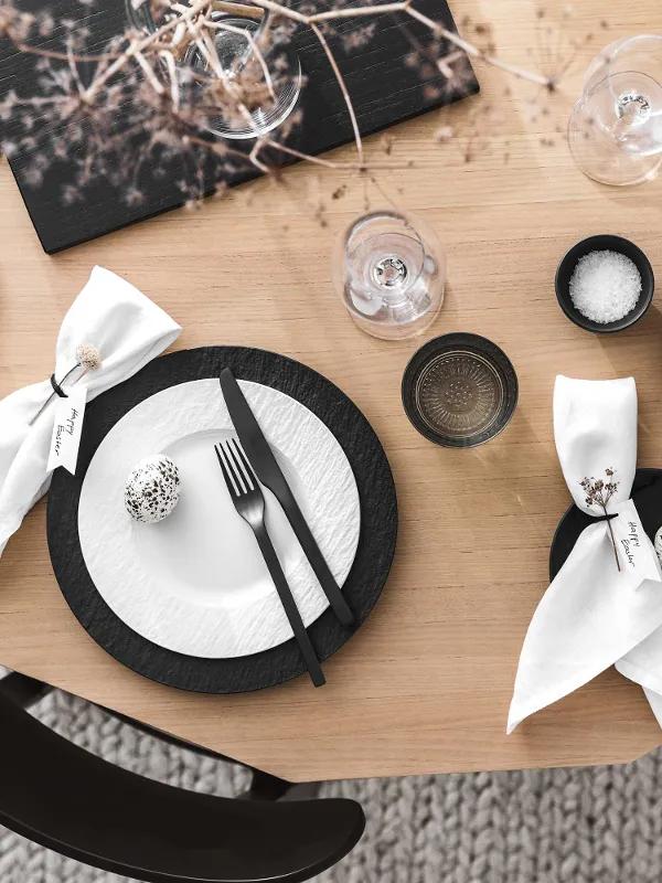 Modern dining table with black and white dinnerware and flatware from the Manufacture collection and minimalist Easter decorations.