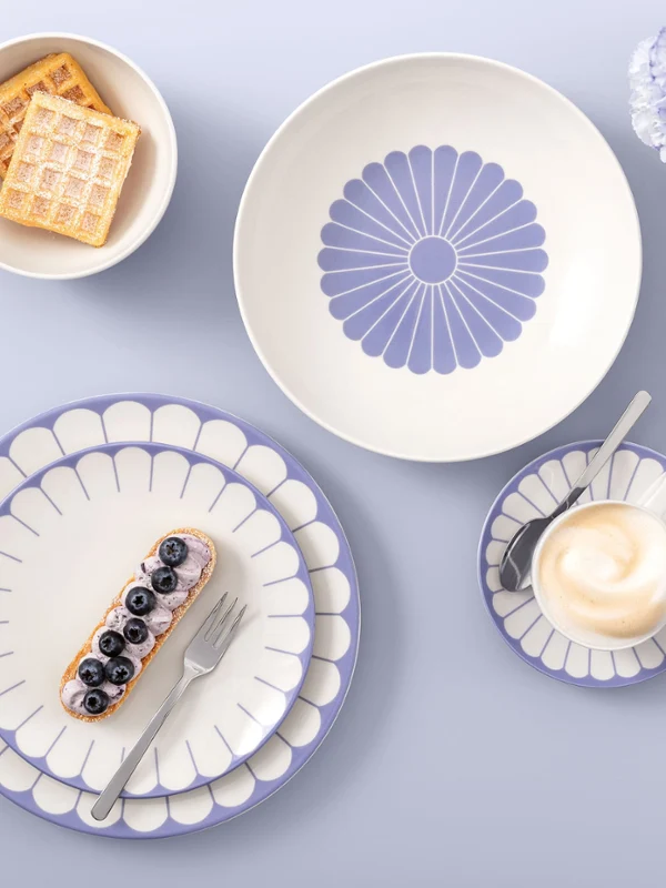 Table setting with Villeroy & Boch Fleur Bleu plates, coffee, dessert, waffles, and light purple flowers on a light background.