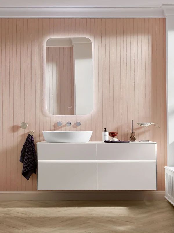 Weißes Artis Waschbecken auf Collaro Unterschrank Modernes Badezimmer mit einer Wandverkleidung aus Holz, einem hängenden Waschtisch, einem runden Waschbecken, einem beleuchteten Spiegel und Blumen auf der Fensterbank.