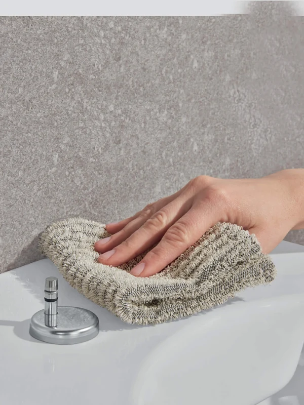 Toilet being wiped with a flannel
A person wiping the edge of a washbasin with a beige cloth in the bathroom.