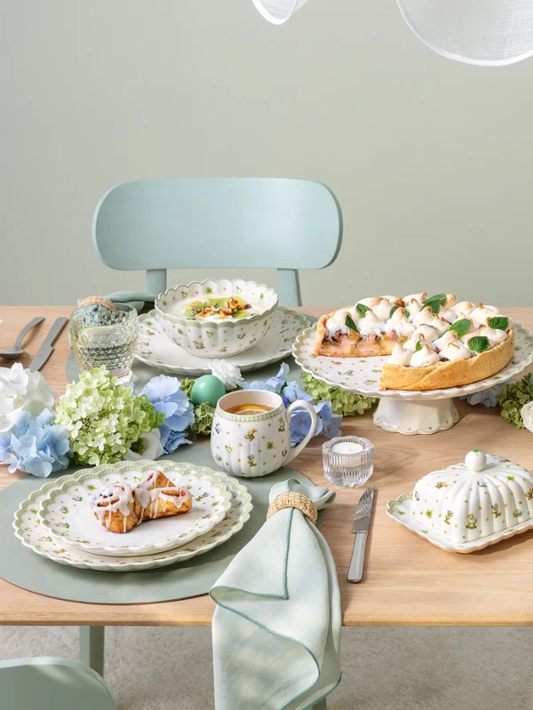 A Easter Delight dining table set for four with Easter Delight decorations, pastel tableware, and plates of food arranged neatly.