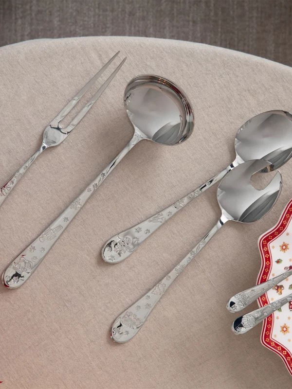 Toy's Delight cutlery On a beige table, next to an ornate plate and some red flowers, lies a set of serving cutlery and dining cutlery.