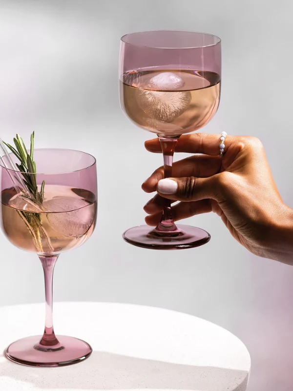 Een arm van een vrouw die een wijnglas vasthoudt en de prachtige kleuren van de collectie laat zien.