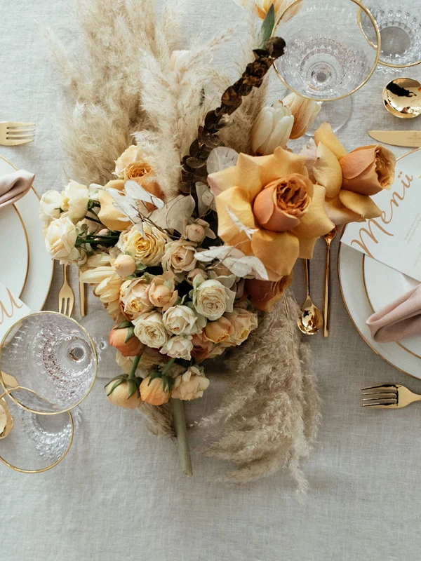 Elegante Tischdekoration mit goldenem MetroChic Besteck, Anmut Geschirr mit Goldrand, floralem Tafelaufsatz und Menükarten.
