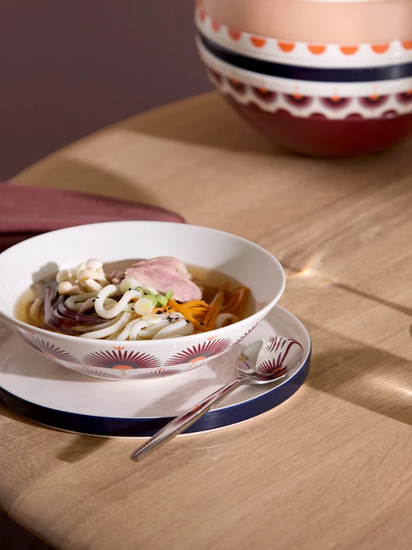La Boule Kyoto soup On the table is a La Boule Kyoto bowl of noodle soup with meat and vegetables, along with a glass of white wine and a glass of water.