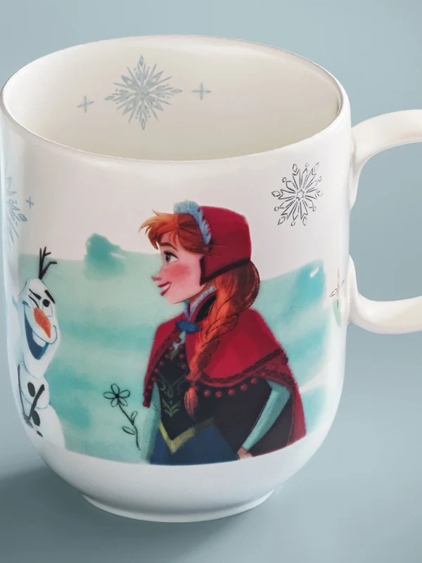 Taza blanca de la colección Disney Frozen con una imagen de dibujos animados. Taza blanca de la colección Disney Frozen con la imagen de una niña con capucha roja y un muñeco de nieve animado con un estampado de copos de nieve.