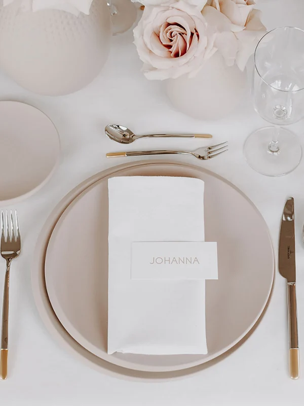 A table at a wedding reception set with NewMoon crockery and glasses A festive table setting with white and beige NewMoon plates, Ella cutlery and NewMoon glasses.