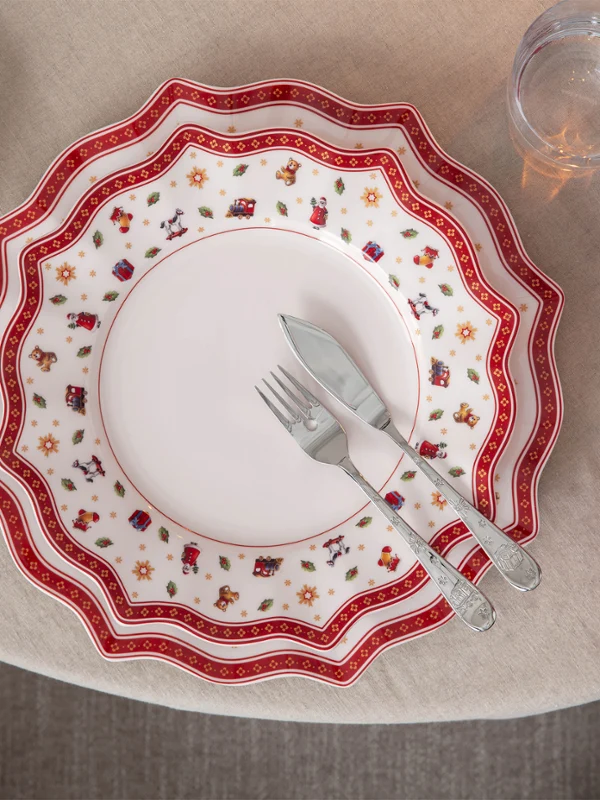 A festively laid table A festively laid table with red-and-white patterned crockery, a red napkin, and a knife and fork on a round table.
