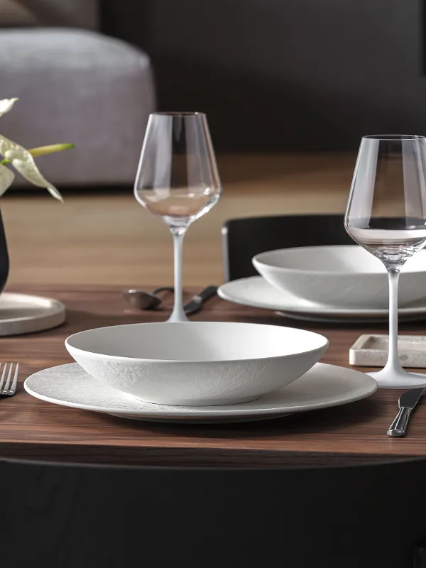 Un set curato con Manufacture Rock, vaso Collier, Travertine, lanterna Noir e portacandele in una raffinata mise en table moderna.