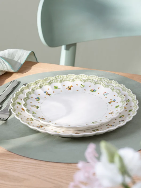 A dining table set with a Easter Delight Crockery decorative plates on a placemat.