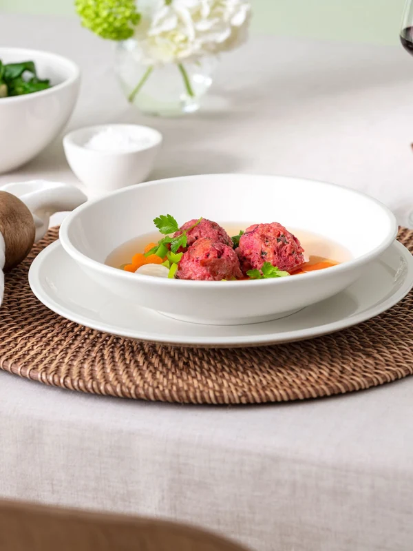 Close-up view of a table setting featuring Villeroy & Boch Artesano Original dinner plate and pasta bowl. The image captures the fine craftsmanship and natural design of the porcelain, styled in a warm, authentic table scene.