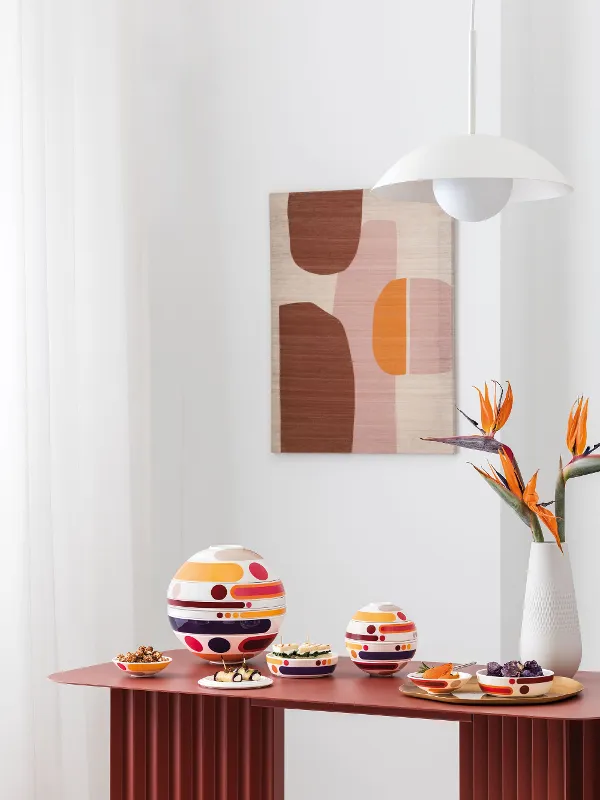 Intérieur moderne avec La Boule et La Petite Boule, un vase blanc Manufacture Collier blanc avec des fleurs orange, et une œuvre murale abstraite aux tons doux.